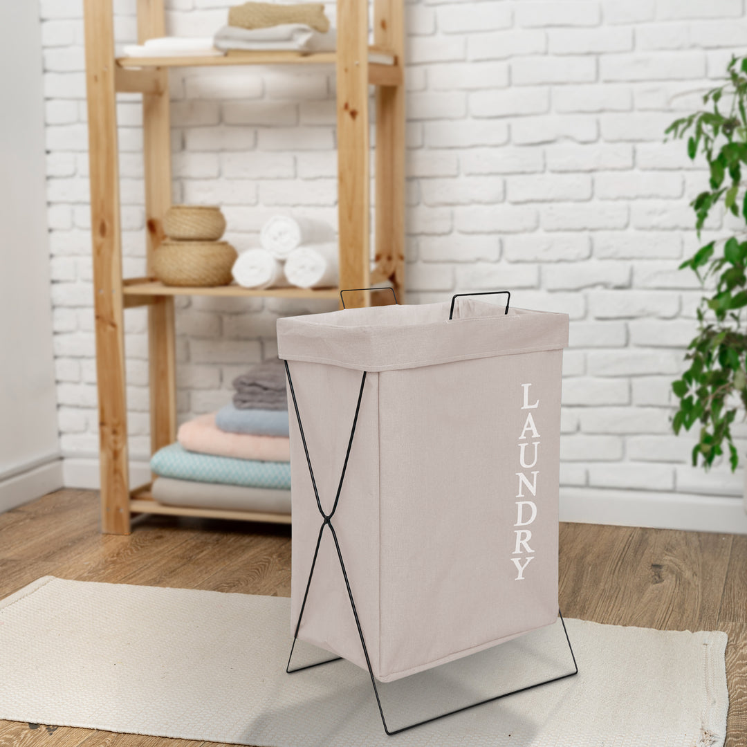 beige canvas laundry bag placed in a washing area with cloth rack in the backgound